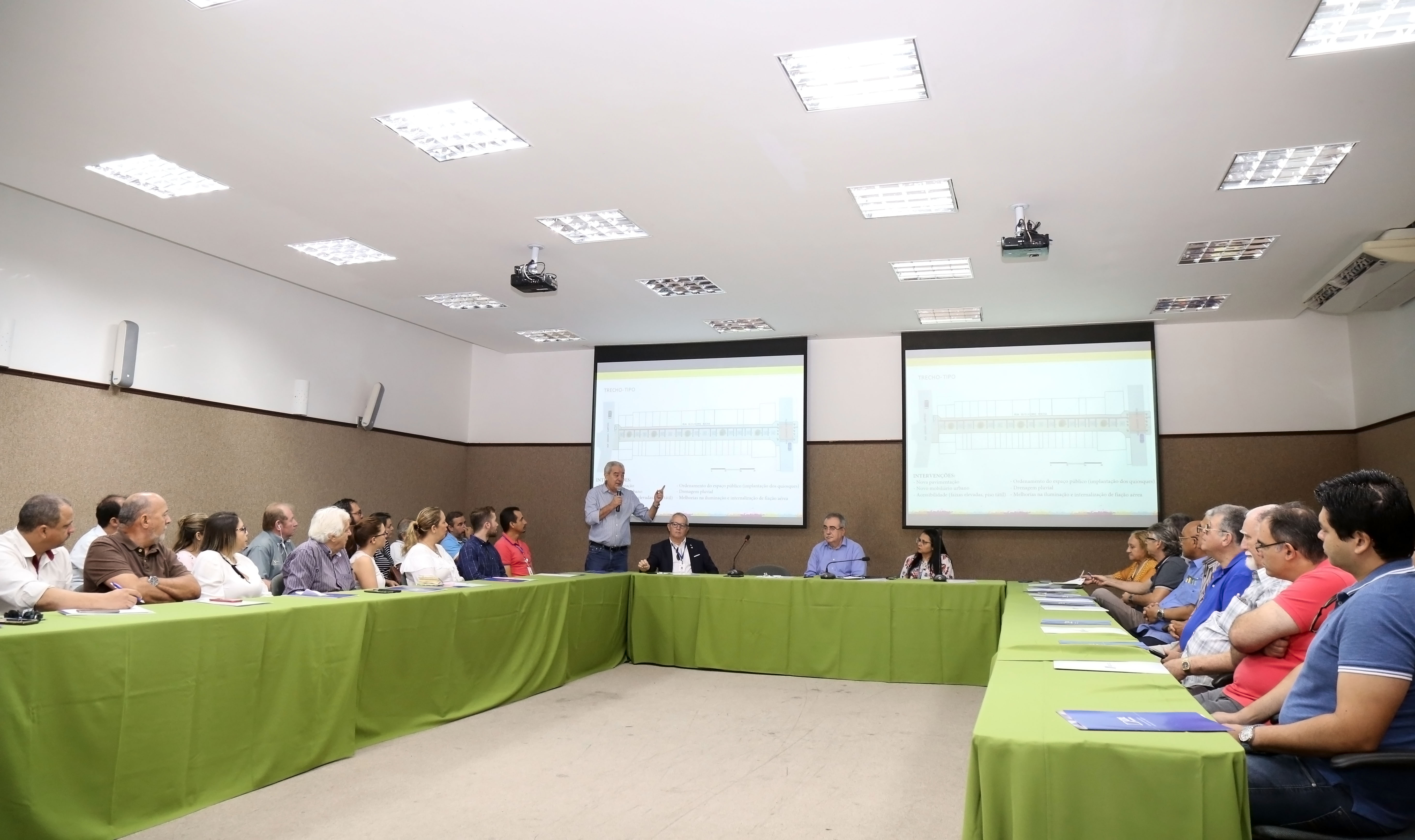 interior de uma sala de reunião com pessoas sentadas ao redor de uma mesa